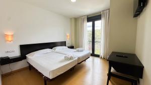 a bedroom with a large bed with a desk and a window at CASA de VIAXEIROS in Ourense