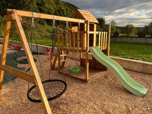 a wooden playground with a swing and a slide at KOTA bien être jaccuzzi , sauna , piscine chauffée , soins bien être in Voissant