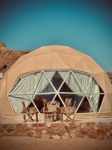 a dome tent with chairs and tables in it at RUM ROSE BUBBLE lUXURY CAMP in Wadi Rum