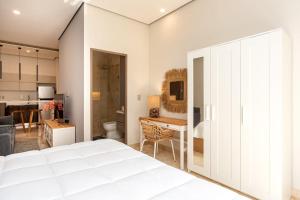 a bedroom with a white bed and a kitchen at Amira District in Cedro