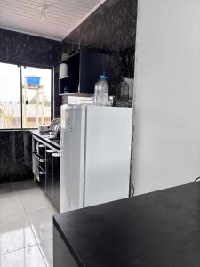 Passo De TorresにあるApartamento 600 metros do mar, 14 minutos do centro de Torresの黒い壁のキッチン(白い冷蔵庫付)