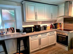 a kitchen with white cabinets and a counter top at Leamington Beech Villa in Penmaen-mawr