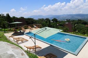a swimming pool with chairs and an umbrella at VIU Boutique Cabins in San Salvador