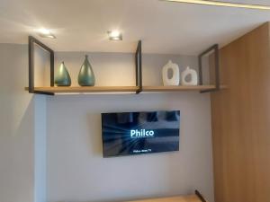 a shelf with vases and a tv on a wall at V-Home Flat Hotel in Macaé +47 photos