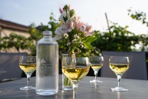 a bottle of white wine and three wine glasses on a table at Agriturismo Al Tralcio in Valeggio sul Mincio