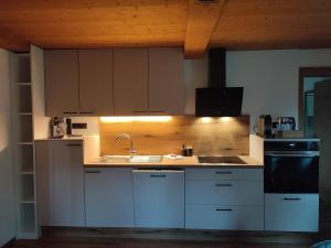 a kitchen with white cabinets and a sink and a stove at Ferienwohnung Hinteregghof in Hart im Zillertal