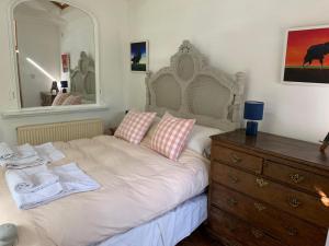 a bedroom with a bed with a dresser and a mirror at Crow Cottage in Briston