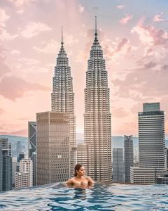 a woman in a infinity pool with a city skyline at The Luxe Infinitum By Elite Home KLCC in Kuala Lumpur