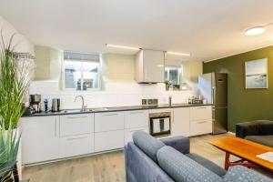 een keuken met witte kasten en een bank en een tafel bij Just steps behind the Royal Palace in Oslo