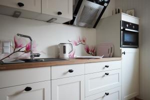 a kitchen with white cabinets and pink flowers on the wall at Upland-Flair Ferienwohnung BLUMENWIESE im Zentrum! in Willingen +29 photos