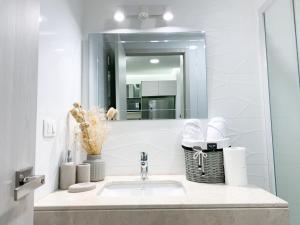 a bathroom sink with a mirror and a basket of towels at Luxury Suites frente mall del sol a pocos minutos del aeropuerto y terminal terrestre in Guayaquil +165 photos