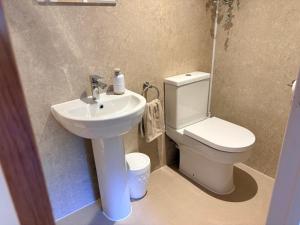 a bathroom with a white toilet and a sink at The Perk Inn Garden Lodge in Broadstone +17 photos