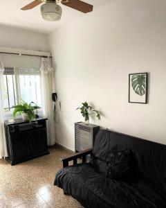a living room with a black couch and a ceiling fan at Casa céntrica San Nicolas - Excelente ubicación y comodidad in San Nicolás de los Arroyos