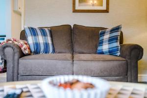 a brown couch with blue and white pillows in a living room at Hough Green Cottage in Ashley