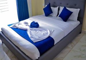a bed with blue and white sheets and blue pillows at Legoland Residence in Migori +72 photos