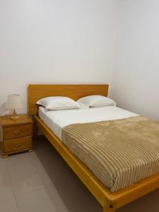 a bed with two pillows and a nightstand with a bed sidx sidx sidx at Sun & Sea Tarrafal in Tarrafal