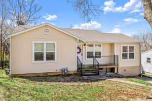 a house with a porch and a tree at Walk to Dickson St - Pet-Friendly Home with Yard in Fayetteville