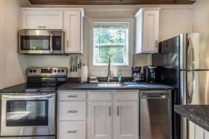 una cucina con mobili bianchi e un lavandino di High Hollow Cottage Modern Tiny Home with Hot Tub a Robbinsville Altre 17 foto