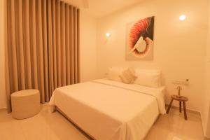 Un dormitorio con una cama blanca y un cuadro en la pared. en Savno Residency, en Uswetakeiyawa 36 fotos más