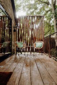 two chairs sitting on a deck with a fence at Woodhill Country House in Otterburn
