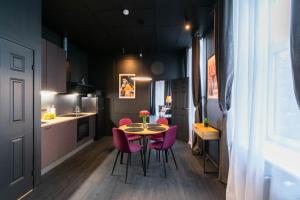 a small kitchen with a table and pink chairs at Apartments24 Black 1903 in Rakvere +64 photos
