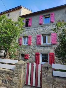 a stone building with pink windows and a white bench at Maison de montagne in La Llagonne