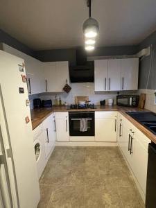 a kitchen with white cabinets and a black oven at Affordable Single Room in Saltney