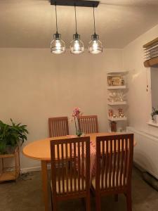 a dining room table with three chairs and three lights at Affordable Single Room in Saltney