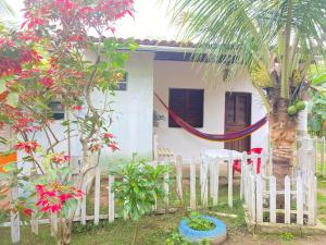 a fence in front of a house with a palm tree at Chalé refúgio das raposas in Meruoca