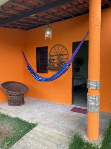 a house with a blue hammock on the side of it at Chalé refúgio das raposas in Meruoca