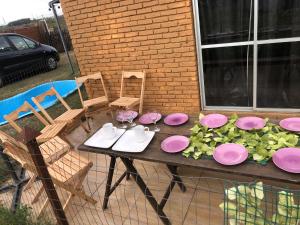 a table with pink plates and flowers on it at Alojamiento Simona Arrayanes in Fray Bentos