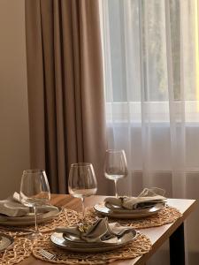 a table with two wine glasses and plates on it at Saulės Tako apartamentai in Druskininkai
