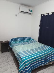 a bedroom with a bed with a blue and white striped blanket at Departamento para 2 personas in Concordia