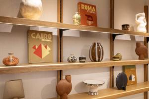 Una exhibición de jarrones y otros artículos en estantes de madera. en Hôtel Brady, en París