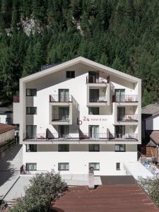 un edificio blanco con una montaña al fondo en Smarthotel brenner24, en Brennero
