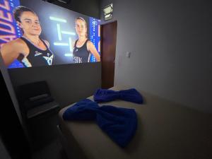 a room with a tv and a bed with blue sheets at Mini Suite Aconchego in Garanhuns