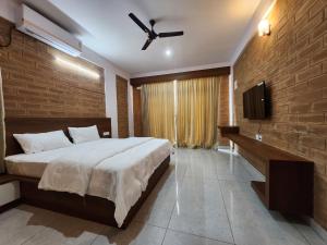 a bedroom with a large bed with a ceiling fan at Brick House at Nandi in Bengaluru