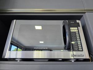 a microwave with a phone sitting on top of it at Novissima casa com piscina proximo do Centro de Foz in Foz do Iguaçu