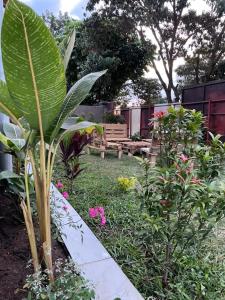 een tuin met een houten bank op de achtergrond bij Tivana in Kigali
