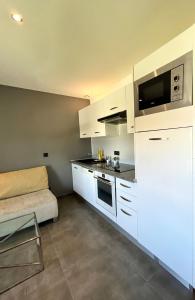 a kitchen with white cabinets and a couch at T2 cosy avec parking à 15 min de Lyon in Pierre-Bénite
