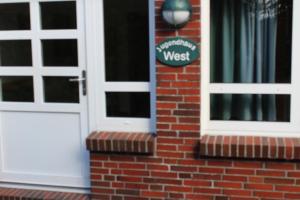 a front door of a brick house with a west sign at Jugendhaus West in Spiekeroog