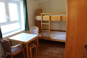 a small room with a table and a bunk bed at Jugendhaus West in Spiekeroog