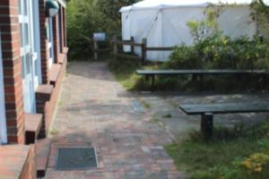 a brick walkway with two benches and a building at Jugendhaus West in Spiekeroog