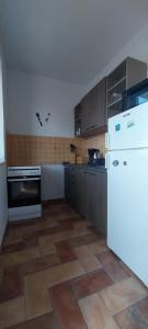 a kitchen with a white refrigerator and a tile floor at Accommodation Centar, Murter in Murter