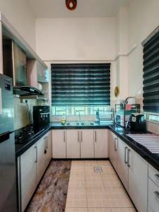 a large kitchen with white cabinets and a sink at Cozy CR Homestay Nilai Pajam with Netflix WiFi in Nilai