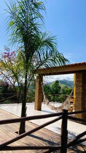 a hammock on top of a wooden deck with palm trees at Sítio metamorfose in Piranguçu
