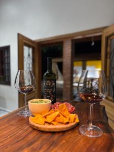 a table with two glasses of wine and a plate of food at Sítio metamorfose in Piranguçu