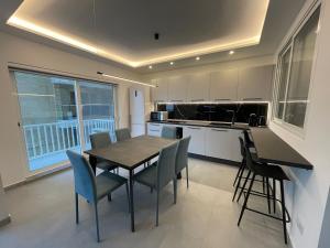a kitchen with a wooden table and chairs in a room at Brand New Seafront Apartment in Sliema