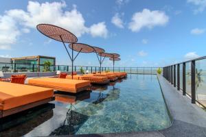PenhaにあるFlat à beira-mar Setai Edition - MyFlats Hospedagensのプールの上にオレンジ色の椅子が並んでいる