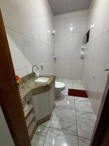 a bathroom with a toilet and a sink at Casa ampla e confortavel in Tangara da Serra +19 photos